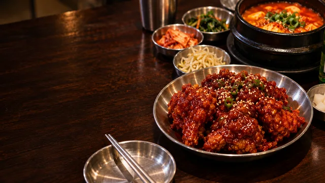 AI-generated illustration of Korean fried chicken, tofu soup and side dishes on a wooden table.