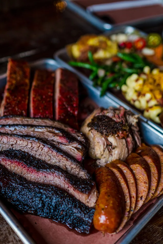 Truth BBQ platter with sliced smoked meats and sides; official brand photograph.